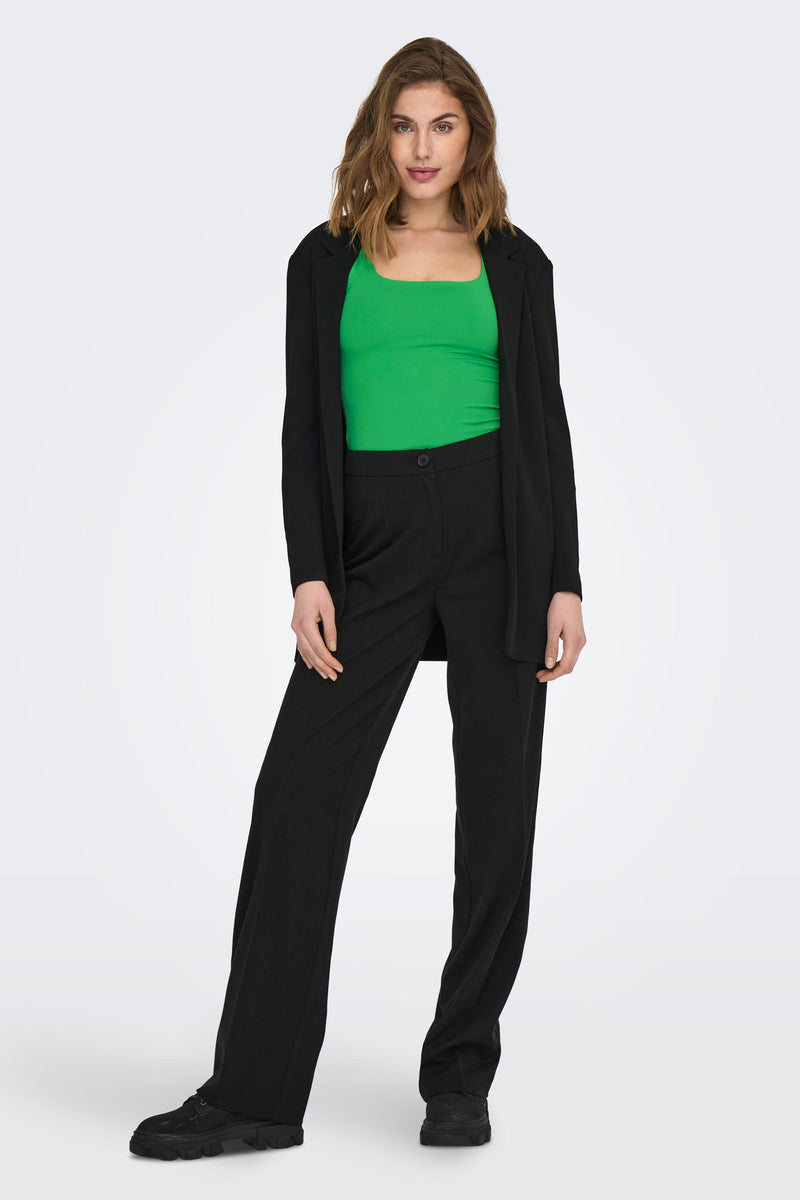 Top vert de ONLY, porté avec un blazer noir et un pantalon taille haute, sur fond uni.