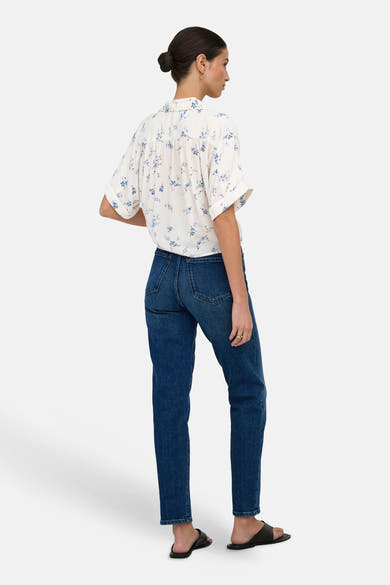 Wit ONLY®-overhemd met blauwe bloemenprint, van achteren gezien met een spijkerbroek en zwarte sandalen.
