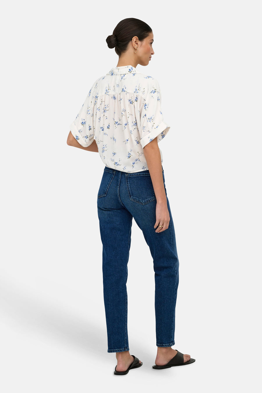Wit ONLY®-overhemd met blauwe bloemenprint, van achteren gezien met een spijkerbroek en zwarte sandalen.