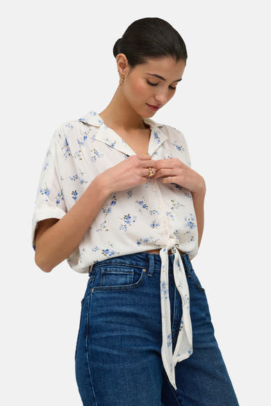 Witte getextureerde blouse met korte mouwen van ONLY® met blauw bloemenpatroon, geknoopt in de taille, gedragen met een spijkerbroek.