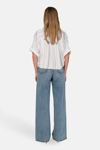 Chemisier blanc à manches courtes de ONLY®, à rayures bleues verticales, porté avec un jean ample.
