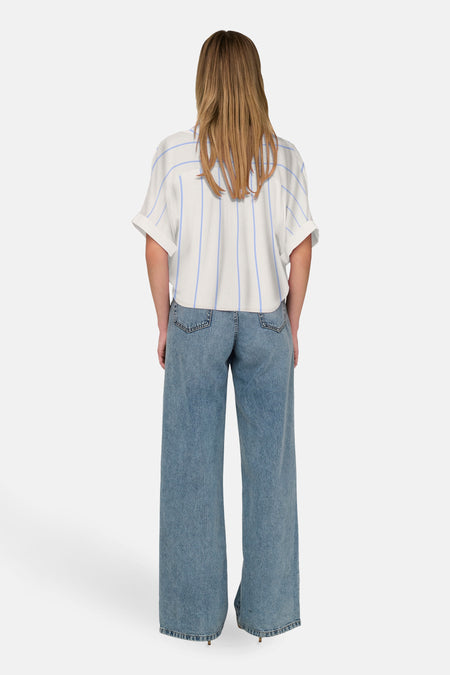 Chemisier blanc à manches courtes de ONLY®, à rayures bleues verticales, porté avec un jean ample.
