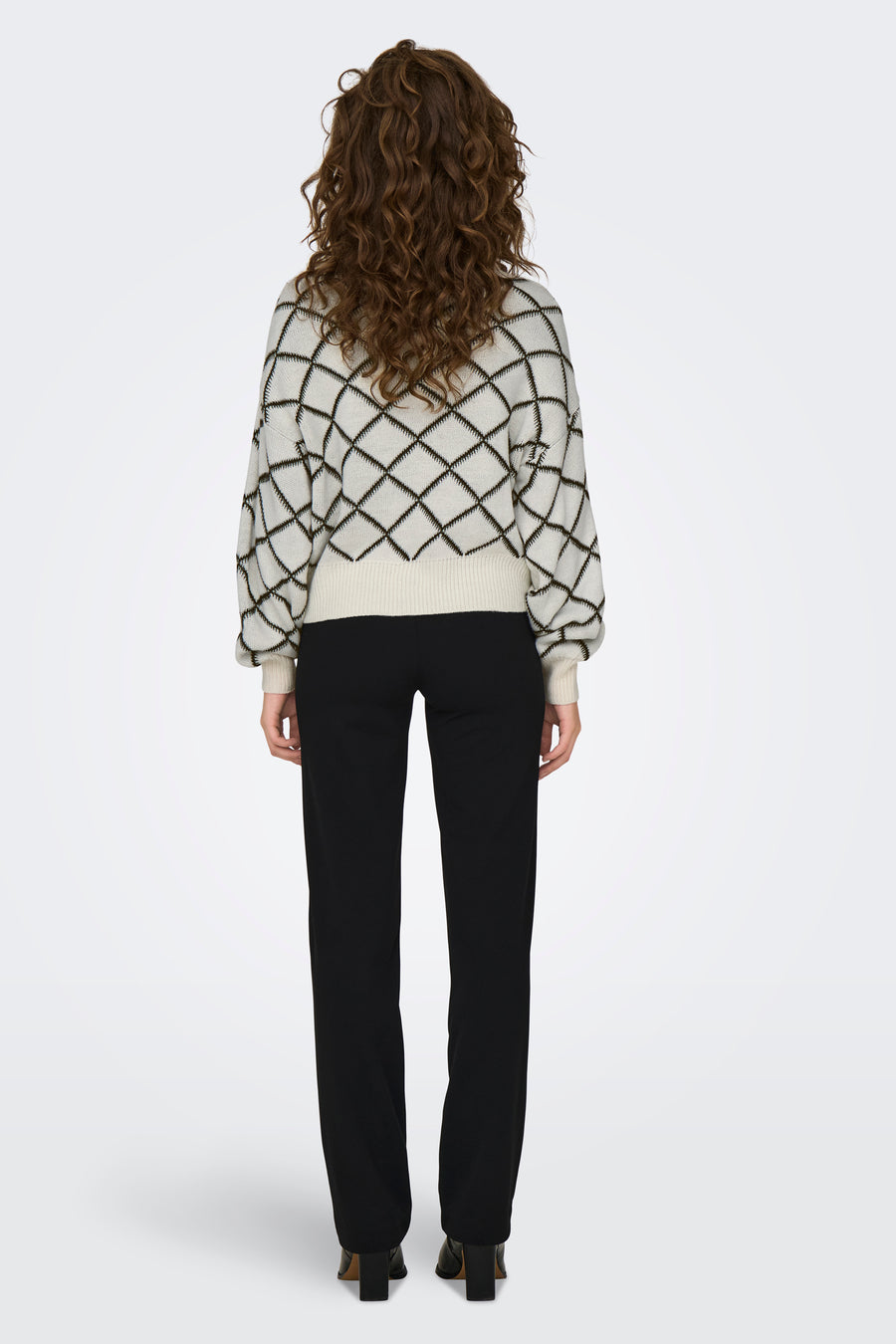 Pull à col rond écru de JDY avec motif à losanges noirs, porté avec un pantalon noir.