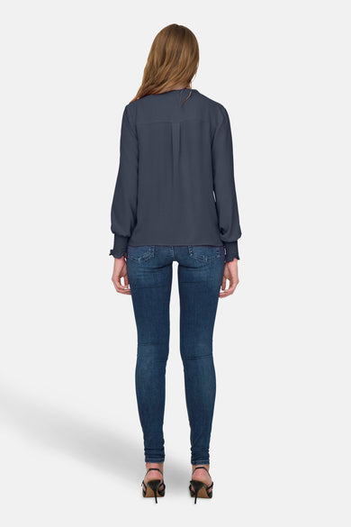 Chemisier bleu à manches longues par ONLY®, porté avec un jean bleu moulant et des talons noirs.
