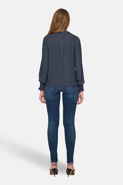 Chemisier bleu à manches longues par ONLY®, porté avec un jean bleu moulant et des talons noirs.
