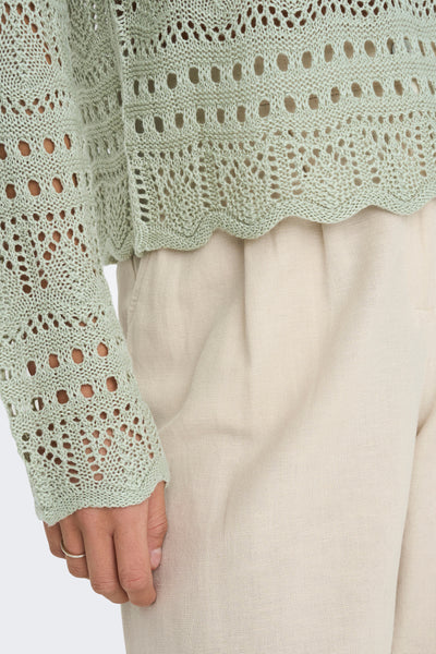 Pull beige col rond de JDY avec motif ajouré, porté avec un pantalon de couleur crème.
