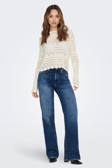 Pull blanc à col rond de JDY, avec un motif ajouré et porté avec un jean bleu.
