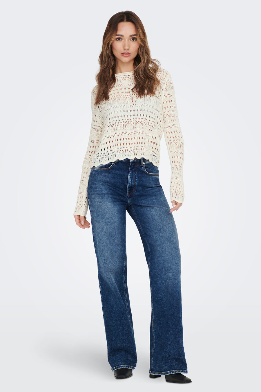 Pull blanc à col rond de JDY, avec un motif ajouré et porté avec un jean bleu.
