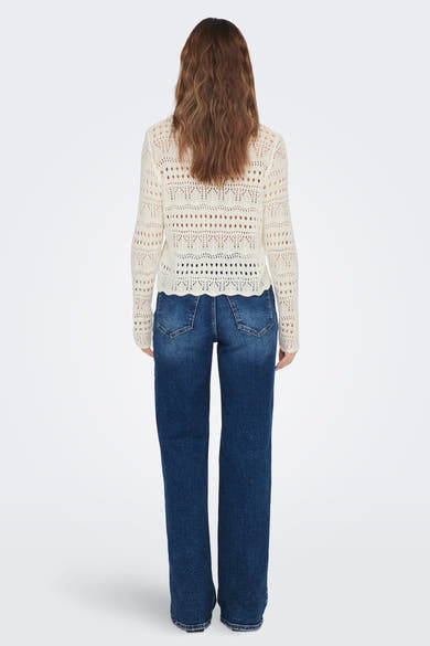 Pull à col rond blanc de JDY, avec un motif ajouré complexe et porté avec un jean bleu.