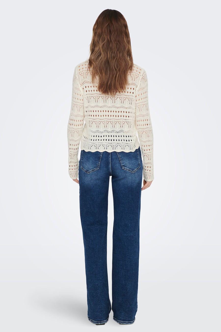 Pull à col rond blanc de JDY, avec un motif ajouré complexe et porté avec un jean bleu.