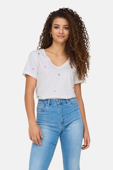 Wit katoenen T-shirt van ONLY versierd met geborduurde klavermotieven, gedragen met een lichtblauwe jeans.