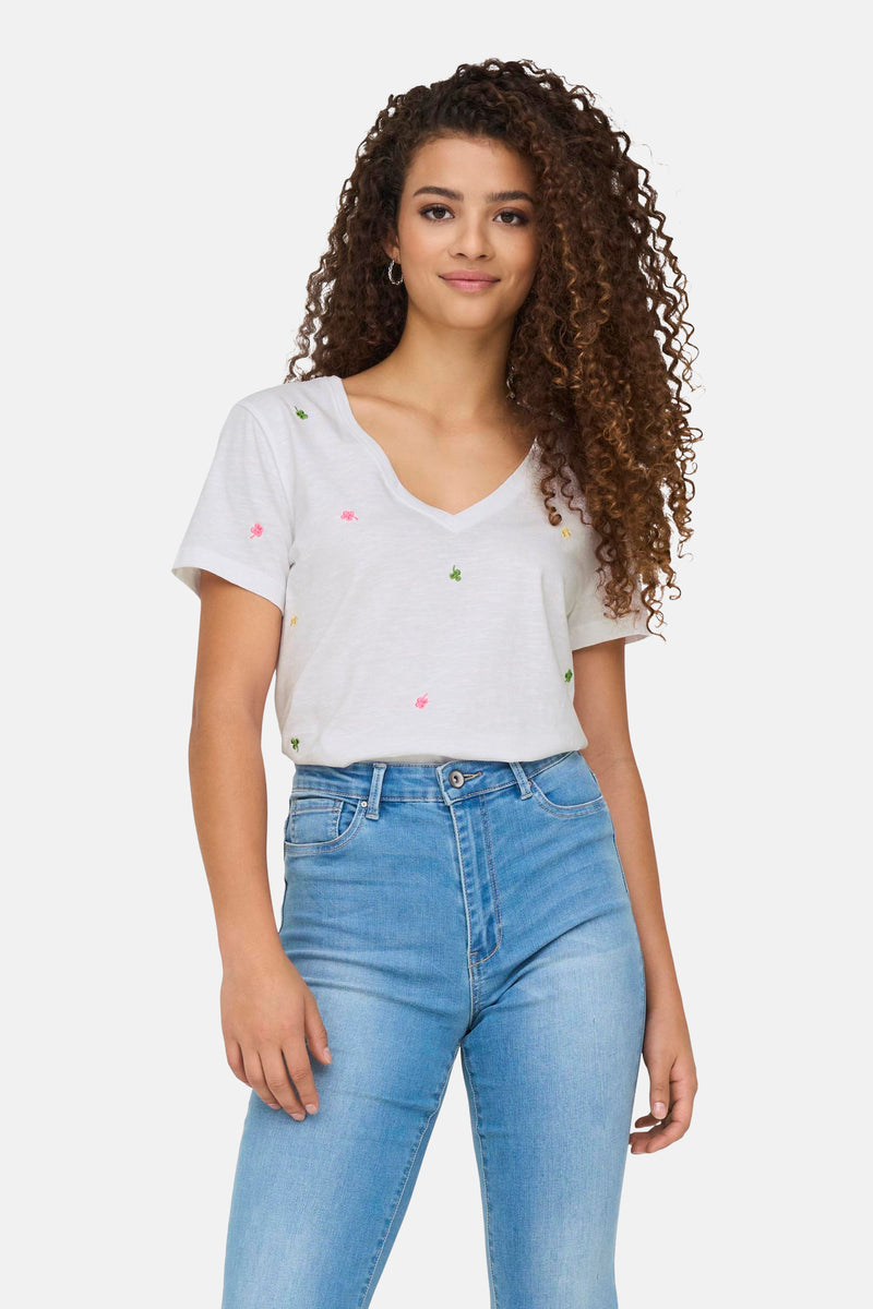 Wit katoenen T-shirt van ONLY versierd met geborduurde klavermotieven, gedragen met een lichtblauwe jeans.