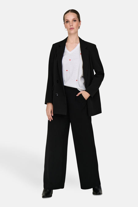 Wit T-shirt met hartjesprint, van ONLY, gedragen met een zwarte blazer en een zwarte wijde broek.