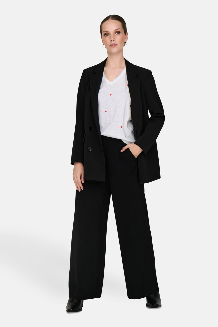 Wit T-shirt met hartjesprint, van ONLY, gedragen met een zwarte blazer en een zwarte wijde broek.