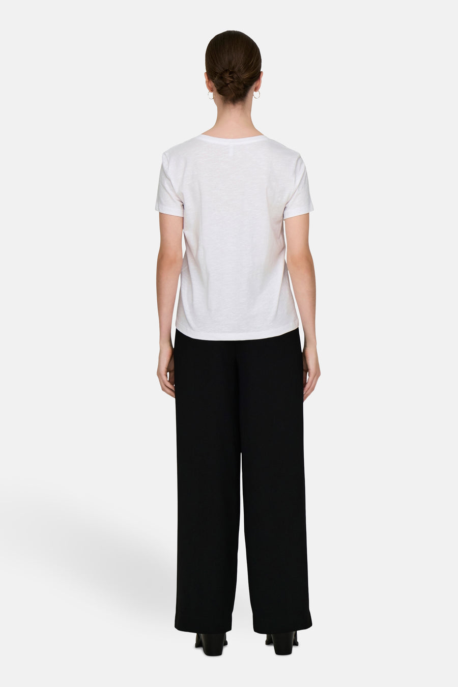 Wit T-shirt van ONLY, gedragen met een wijde zwarte broek, achtergezicht.