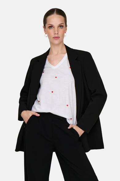 Wit T-shirt met hartmotief van ONLY, gedragen met een zwarte blazer en broek.