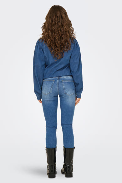 Donkerblauwe skinny jeans van ONLY, gedragen met een spijkerblouse en zwarte laarzen.