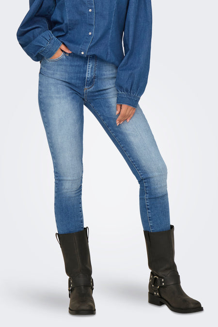 Skinny jeans in donkerblauw denim van ONLY, gedragen met een spijkerblouse en zwarte laarzen.