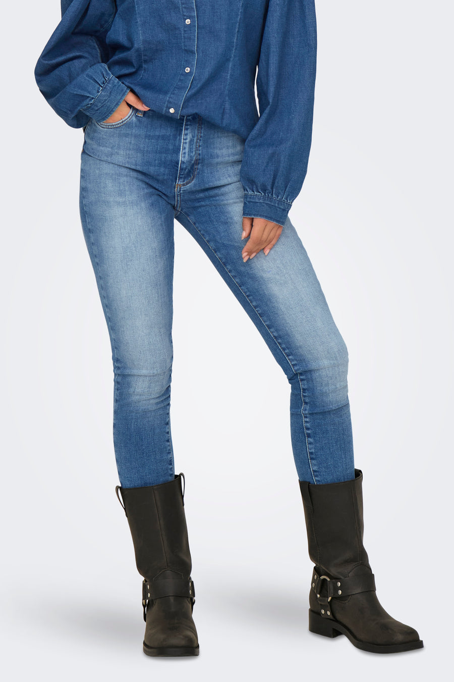 Skinny jeans in donkerblauw denim van ONLY, gedragen met een spijkerblouse en zwarte laarzen.