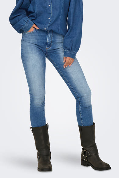 Skinny jeans in donkerblauw denim van ONLY, gedragen met een spijkerblouse en zwarte leren laarzen.
