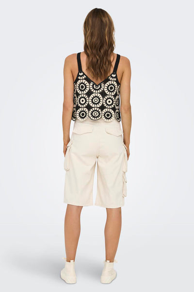 Haut sans manches noir de ONLY® en crochet à motifs floraux blancs, vu de dos avec un short cargo beige.