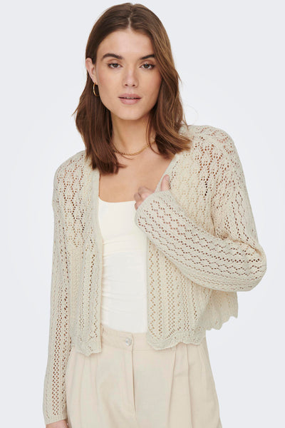 Ecru gebreid vest met open structuur van ONLY, gedragen over een witte tanktop en een beige broek met hoge taille.