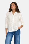 Chemisier à manches longues blanc van JDY, broderie anglaise avec motifs floraux et porté avec un jean.
