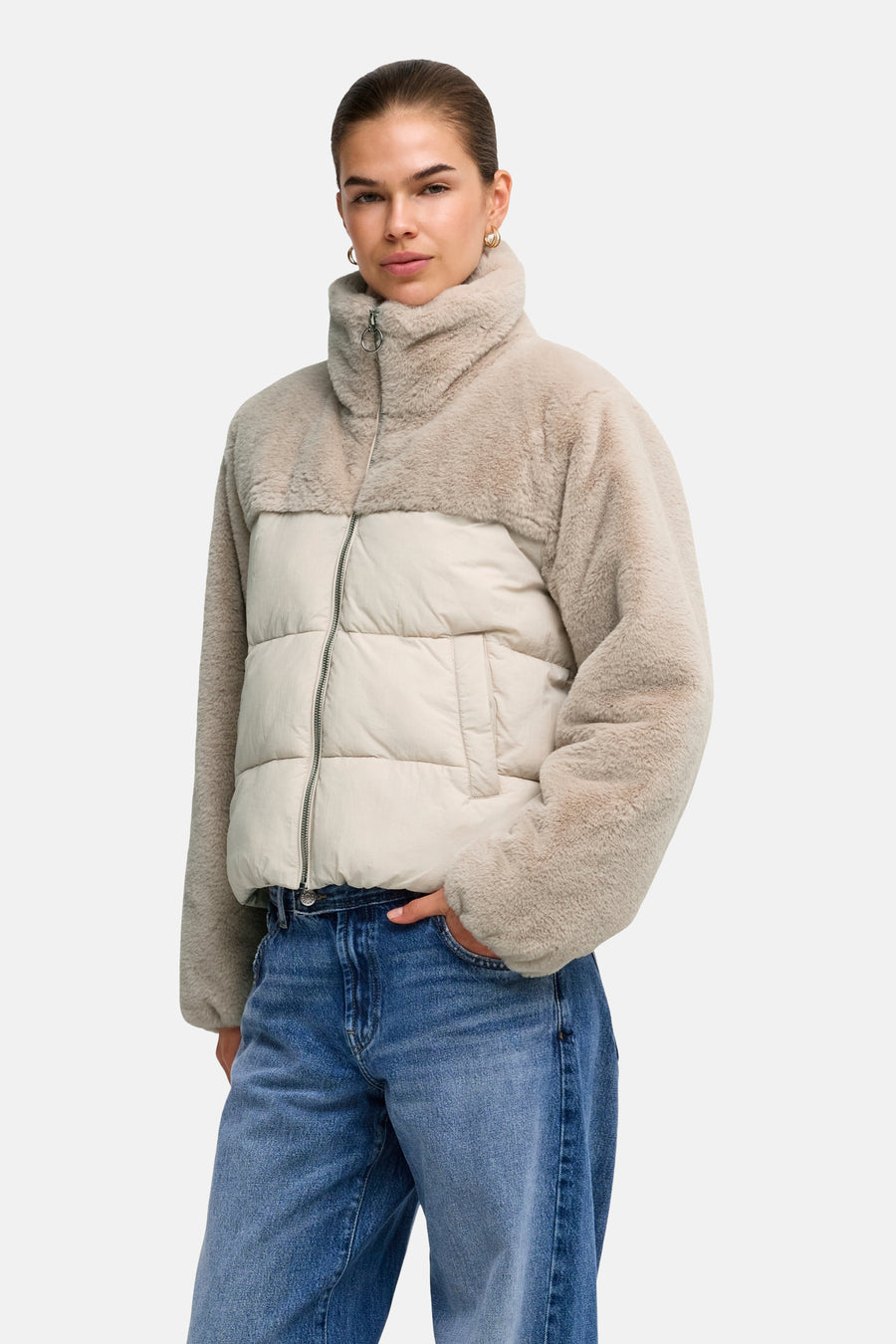 Beige and cream two-tone quilted puffer vest with plush faux shearling collar and sleeves, front zipper, side pocket, worn with blue jeans in lifestyle front view