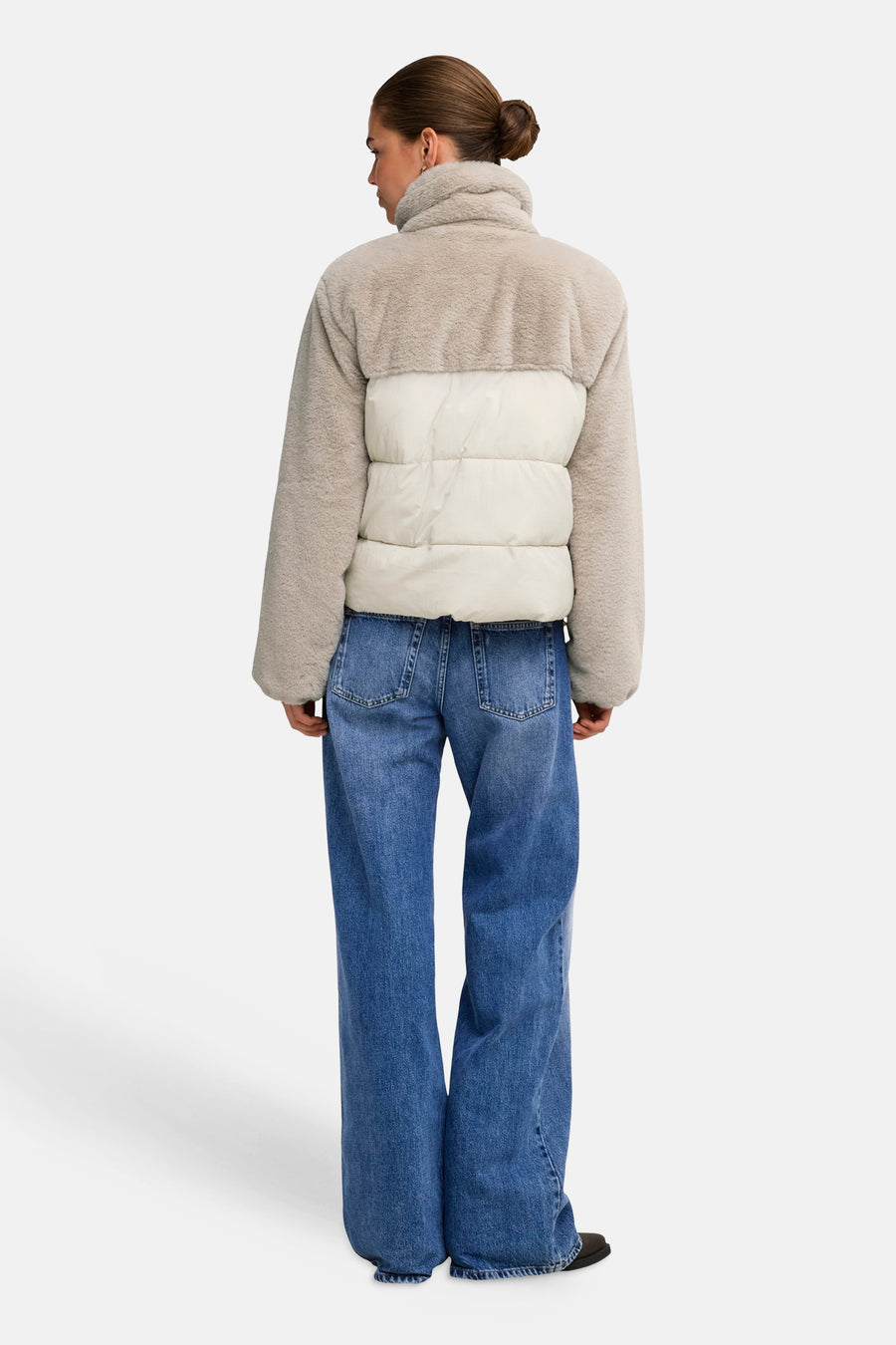 Beige and cream two-tone quilted puffer jacket with plush sherpa collar and sleeves, back view on model wearing blue wide-leg jeans