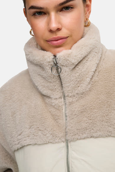 Beige fluffy quilted women's jacket with high collar and silver zipper, close-up front view