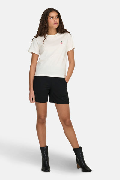 T-shirt blanc à manches courtes de JDY, orné d'une cerise brodée, porté avec un short noir et des bottines.