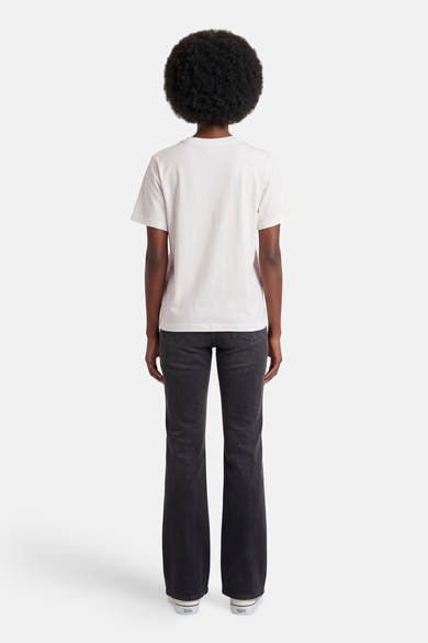 T-shirt blanc de JDY, porté de dos par une femme avec un jean foncé et des baskets blanches.