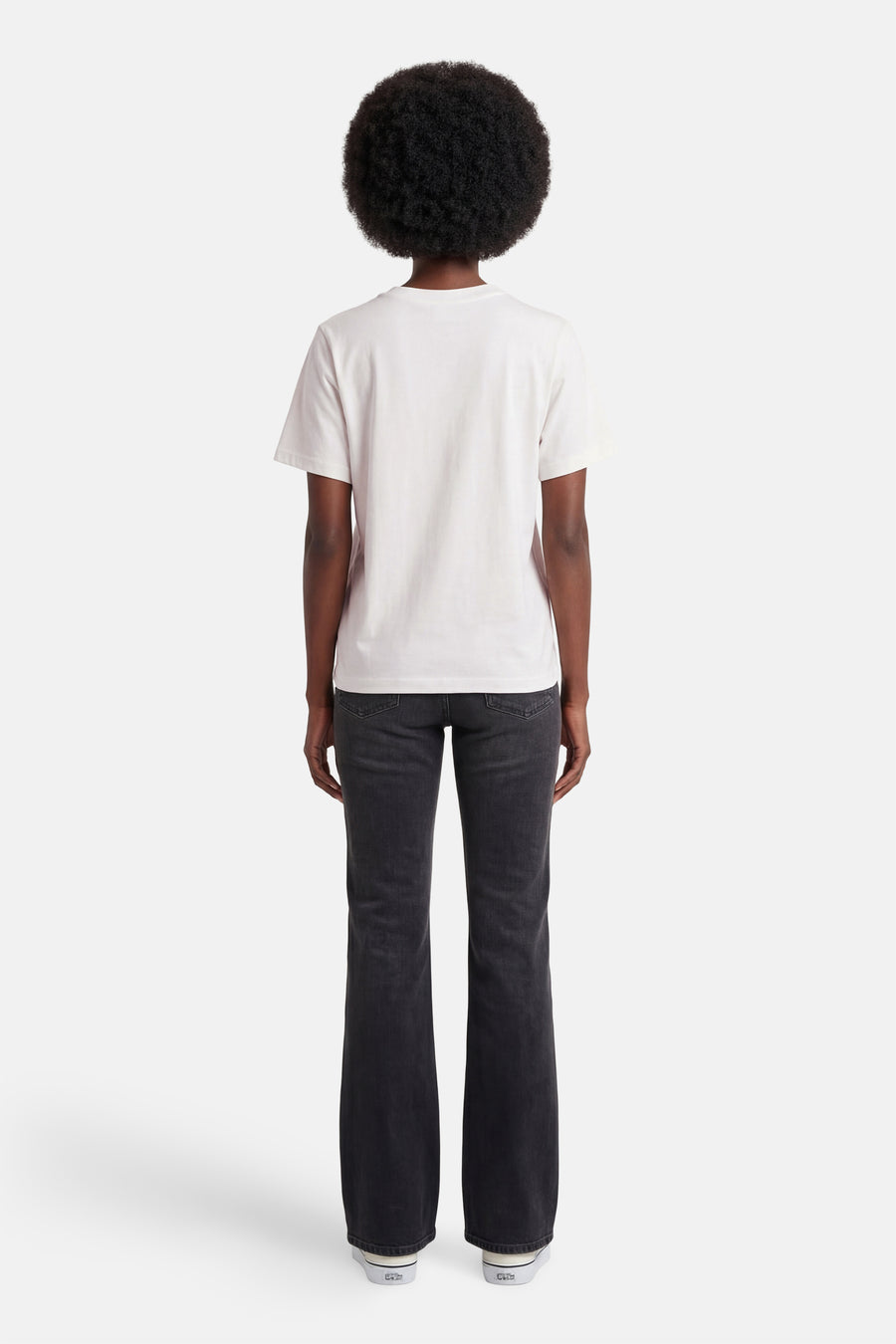 T-shirt blanc de JDY, porté de dos par une femme avec un jean foncé et des baskets blanches.