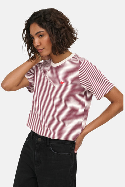 Red and white striped short-sleeve t-shirt with small red heart patch, worn by model with black jeans, side view.