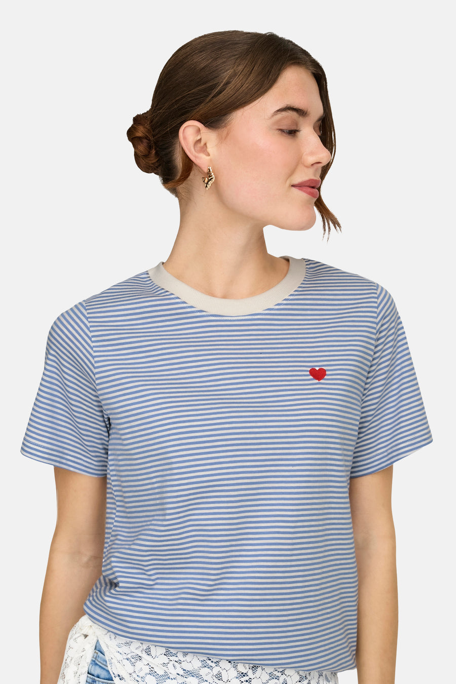 T-shirt bleu à rayures de JDY, orné d'un petit cœur rouge, porté avec un short en jean taille haute.
