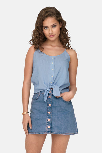 Chemisier sans manches bleu rayé de ONLY, noué sur une jupe en jean boutonnée, avec bracelet doré.

