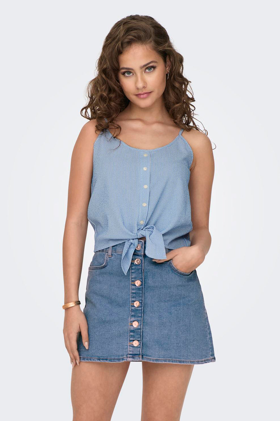 Chemisier sans manches bleu rayé de ONLY, noué à la taille, porté avec une jupe en jean boutonnée.
