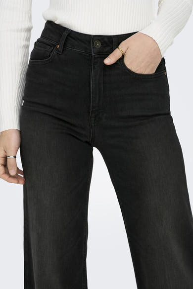 Jean large noir en denim par ONLY® avec une main dans la poche avant.