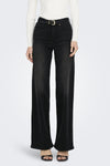 Jean large en denim noir de ONLY®, porté avec une ceinture noire et un pull blanc.
