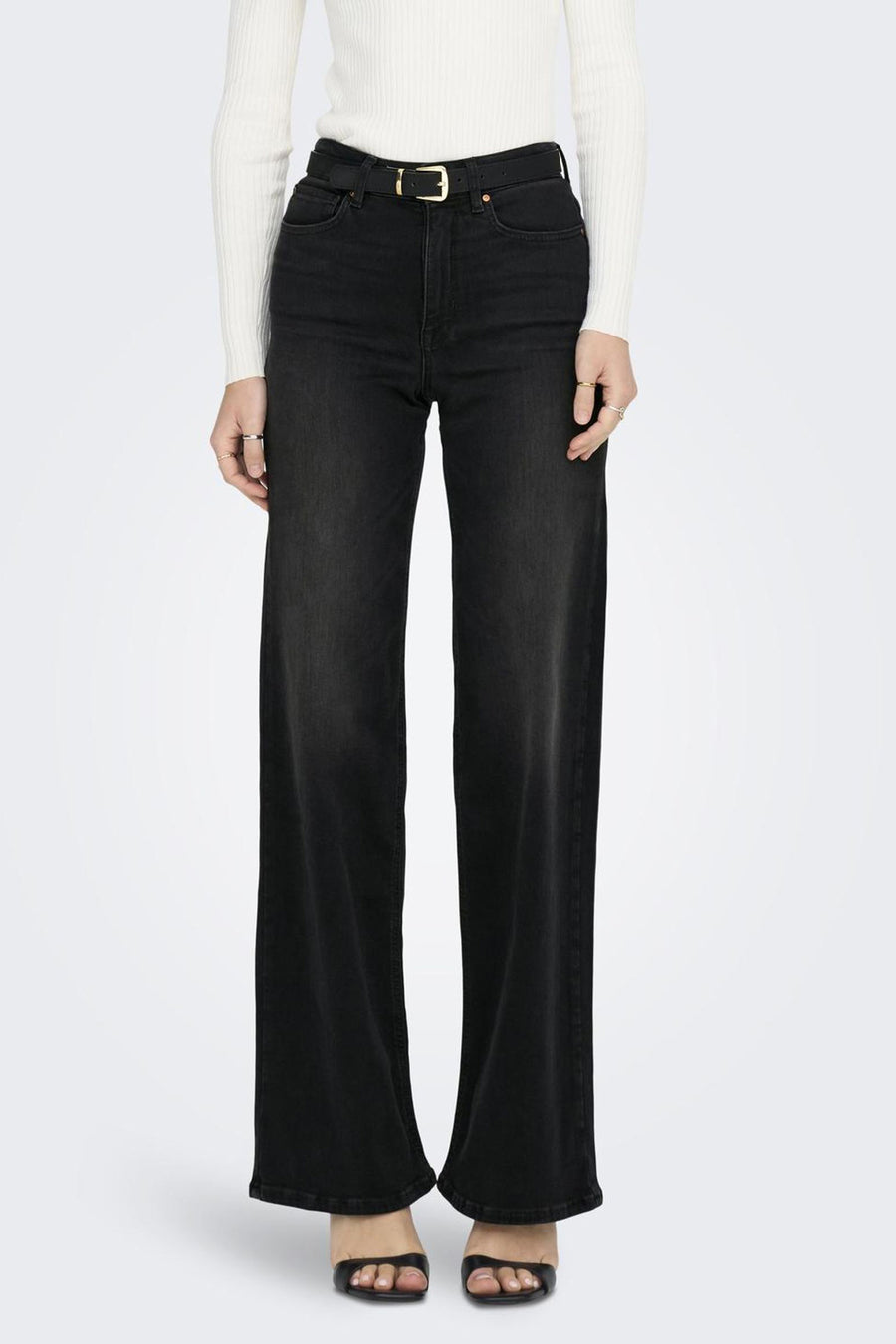 Jean large en denim noir de ONLY®, porté avec une ceinture noire et un pull blanc.
