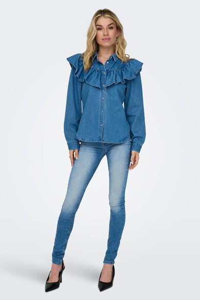 Blue skinny jeans with faded wash and slim fit, worn with denim ruffled shirt and black heels, full-length front view