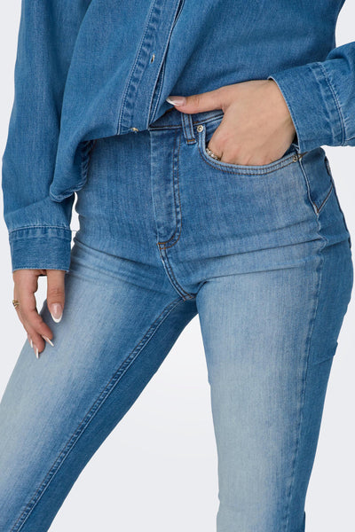 Blue skinny jeans with faded wash and contrast stitching, shown on model from front view, paired with denim jacket