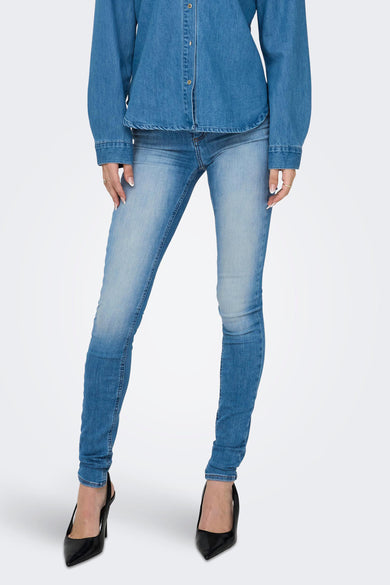Blue skinny jeans with faded wash and slim fit, worn with denim shirt and black heels, front view