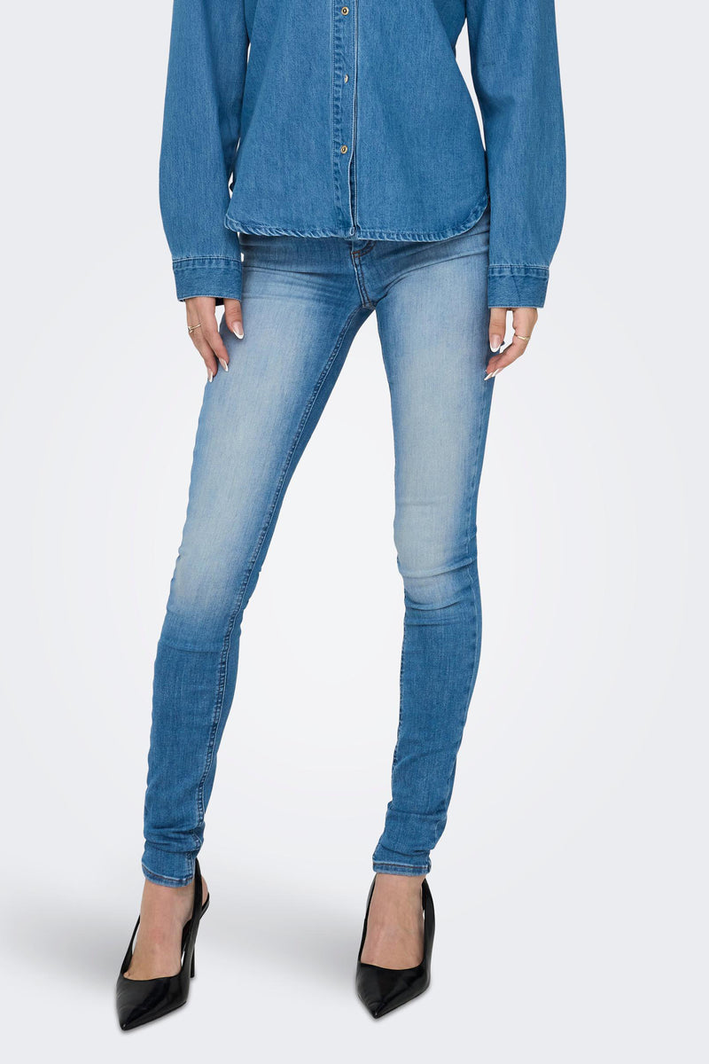 Blue skinny jeans with faded wash and slim fit, worn with denim shirt and black heels, front view