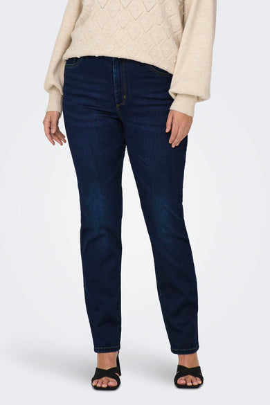 Jean droit bleu de CARMAKOMA, porté avec un pull beige à motifs ajourés et des chaussures noires.