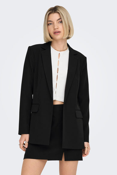 Blazer noir de ONLY, porté avec un top blanc à découpes et un collier doré fin.