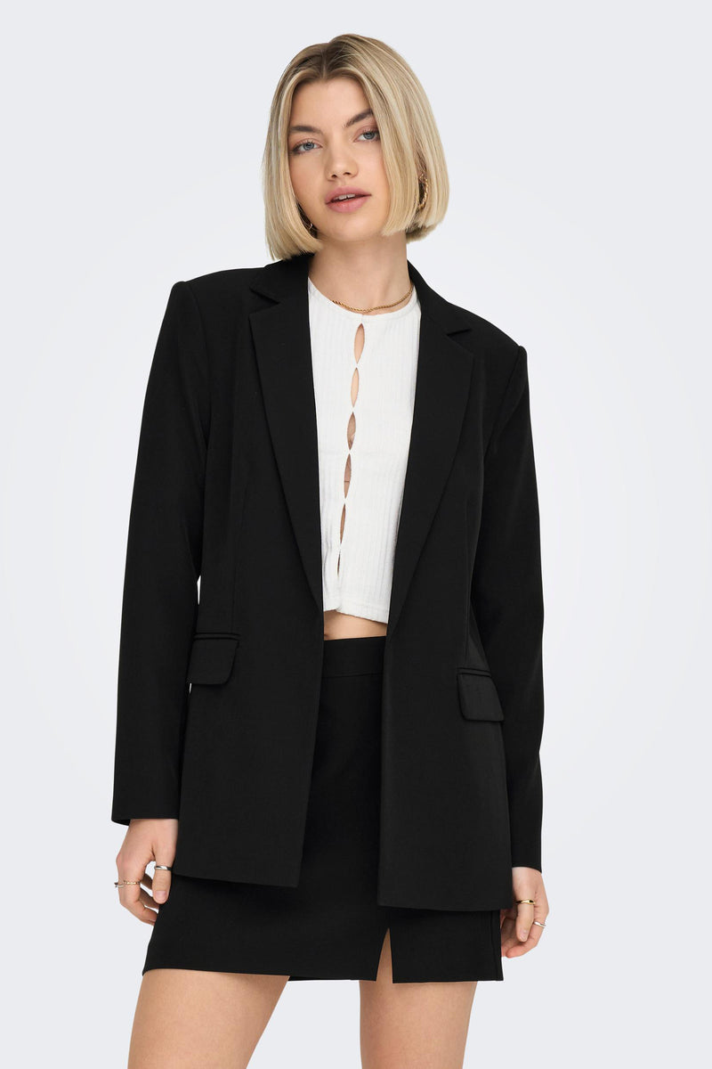 Blazer noir de ONLY, porté avec un top blanc à découpes et un collier doré fin.