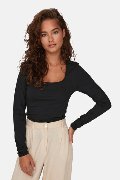 T-shirt à manches longues noir de ONLY, porté avec un pantalon beige à taille haute.
