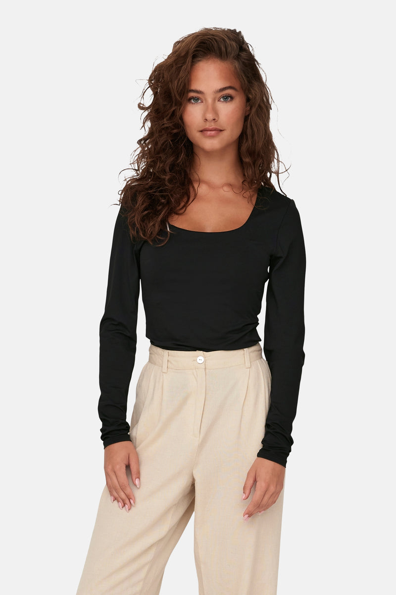 Zwarte T-shirt met lange mouwen van ONLY, gedragen met een beige broek met hoge taille.
