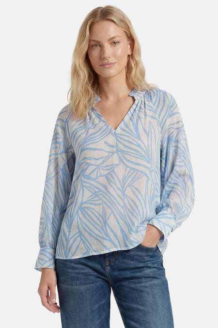 Chemisier à manches longues blanc et bleu de GOA GOA à motif végétal stylisé, col en V, portée avec un jean.